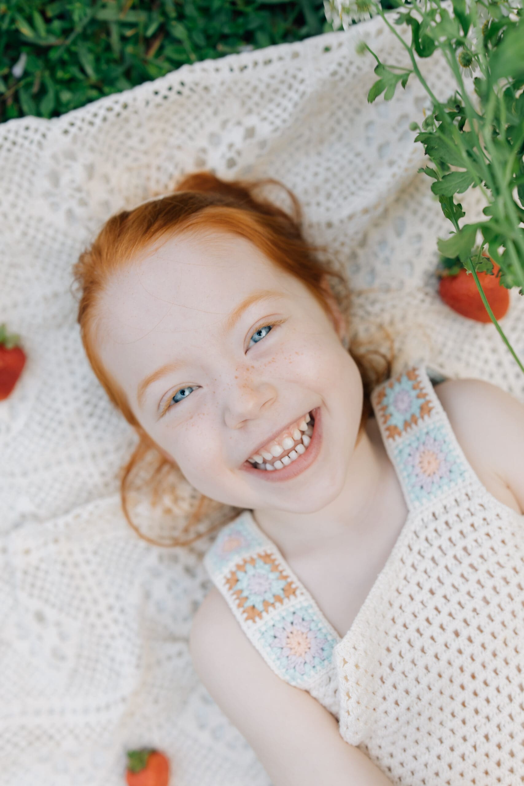 Young girl smiling and holding a strawberry during spring-inspired family photos in Miami