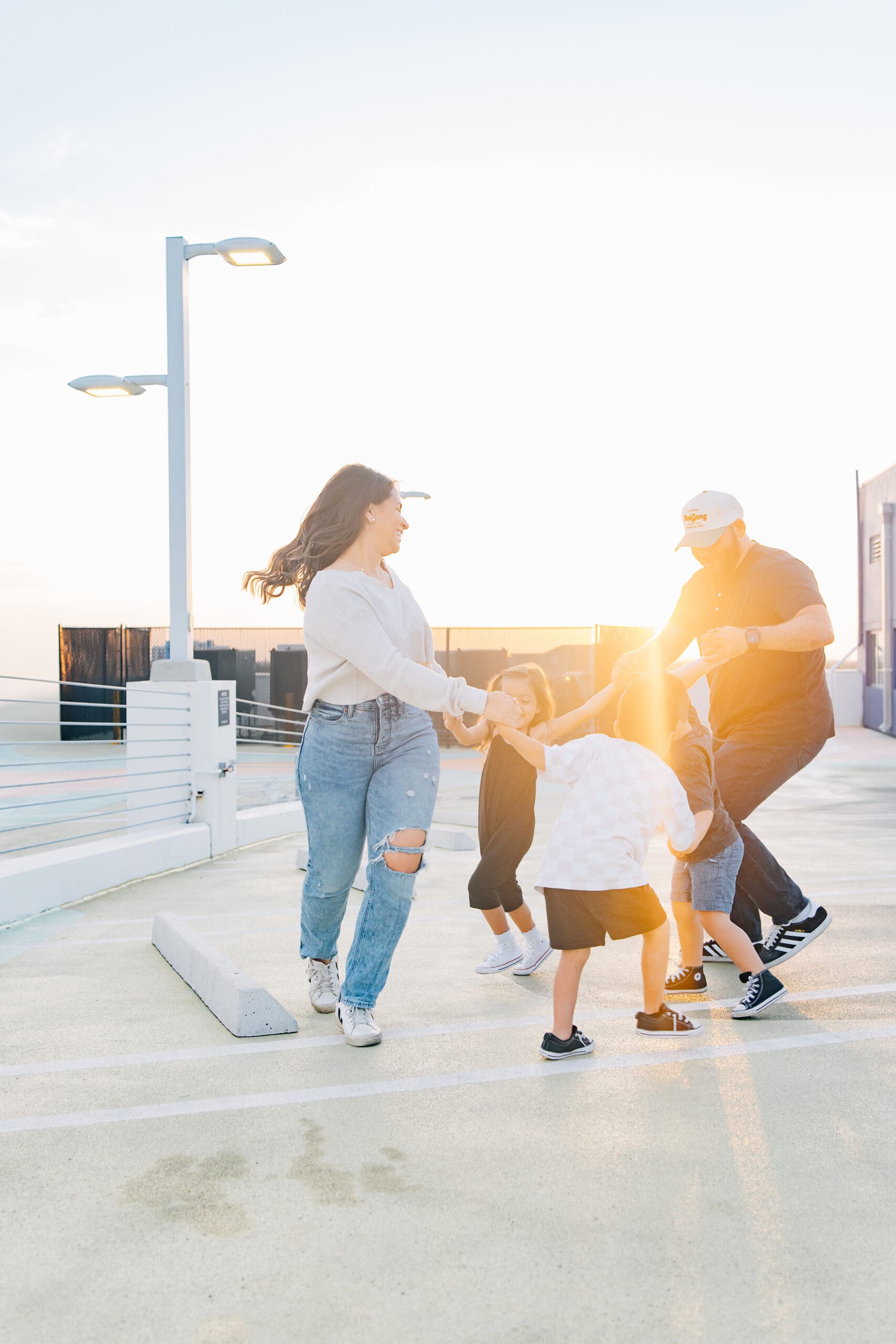 Family playing together in a candid moment on the rooftop of the Museum Garage in Miami Design District at golden hour